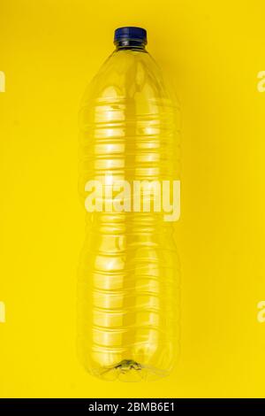 Empty plastic bottle of water on a yellow background. Concept of collecting garbage to the yellow container Stock Photo