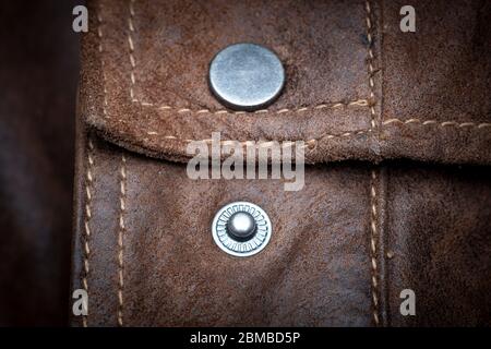 metal press stud fastener on a brown leather jacket, close up. Stock Photo