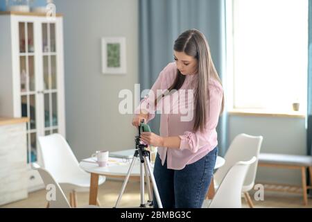 Dark-haired woman in a pink blouse fixing the camera Stock Photo