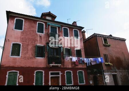 Laundry drying out, hanged on a clothes line stretched between two buildings in Murano, Italy Stock Photo