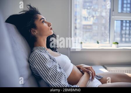 Despondent beautiful female sitting on the sofa Stock Photo