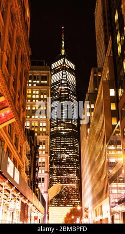 New York City, USA - 10 November 2018: Freedom tower at with lights on looking sown a side street at night.