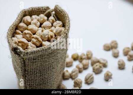 Chickpeas spilled in the burlap bag on white background Stock Photo