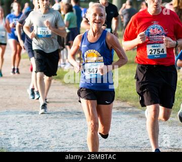 North Babylon, New York, USA - July 2019: Women smiling in a crowd while running a trail race fast around Belmont Lake State Park during the Long Isla Stock Photo