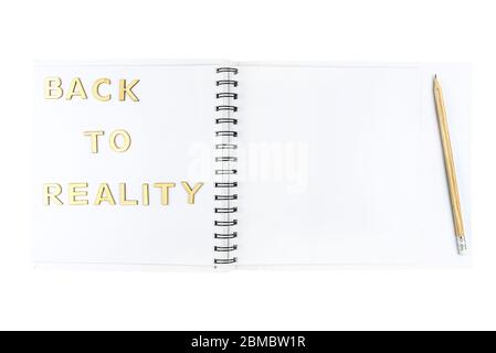 The inscription "back to reality" made of wooden letters lying on an open notebook with white pages, isolated on a white background with a clipping pa Stock Photo