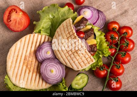 Doner kebab pita with green salad, tomatoes cherry, potato free, grilled beef meat in lunch box on wrap background Stock Photo