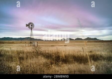 Magenta sky sunset on western landscape windmill in prairie grass Stock Photo