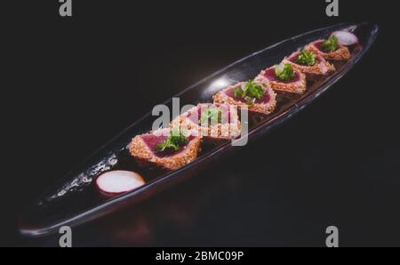 Tuna tataki arranging in the long dish with studio lighting. Stock Photo