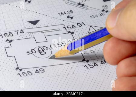Man holding a pencil for pointing a line on architectural plan Stock Photo