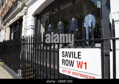 Westminster street sign on Savile Row in London, the Golden mile of bespoke tailoring, is attached to the railings of Gieves and Hawkes - gentlemen's  tailor / tailoring shop front and window display. UK (118) Stock Photo