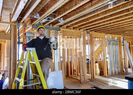 Electrician is holding in his hands installs and mounts the interior lighting on the ceiling Stock Photo