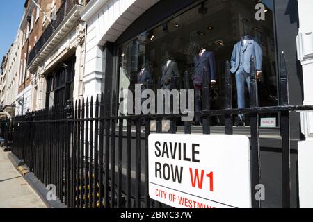 Westminster street sign on Savile Row in London, the Golden mile of bespoke tailoring, is attached to the railings of Gieves and Hawkes - gentlemen's  tailor / tailoring shop front and window display. UK (118) Stock Photo