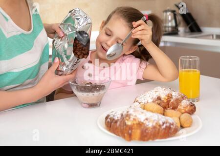 Mother having breakfast with her daughter at a table in kitchen, happy single mother concept Stock Photo