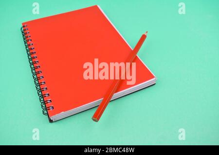 Orange colored wood pencil crayon placed on top of a orange color note paper diary Stock Photo