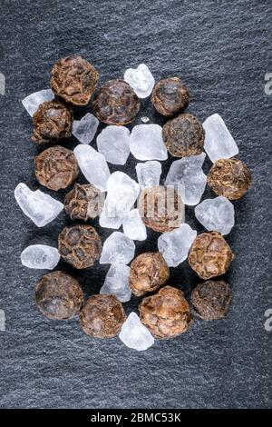 Mixture of salt crystals and pepper corns on a grey slate background Stock Photo