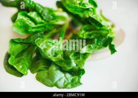 There are fresh spinach leaves on the white table in the kitchen. Ingredient for cooking. Useful vegetable for health. Stock Photo
