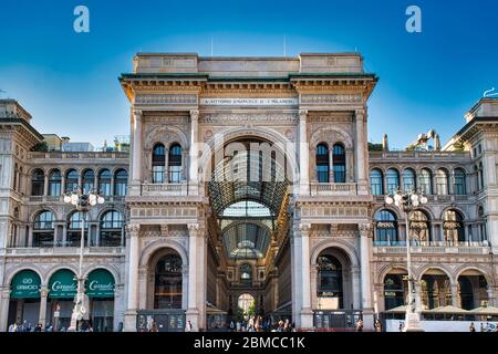 Milan, Italy May 8, 2020: The golden sunshine is reflecting on the front of the magnificent triumphal arch entrance of the Galleria Vittorio Emanuele Stock Photo