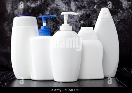 White plastic bottles of liquid soap, shampoo and shower gel. Hygiene concept. Toiletries on black marble background in bathroom, spa procedures Stock Photo