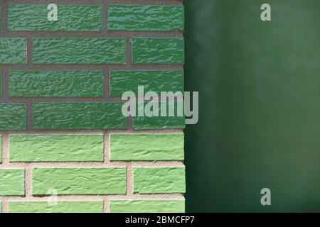 A glazed enamelled green brick wall creating a retro vintage effect on a exterior facade Stock Photo