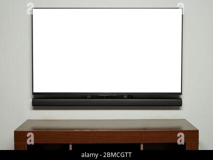 Big tv screen hang on wall with empty wooden table Stock Photo