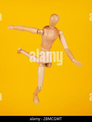 Hit soccer ball by wooden doll isolated on yellow background Stock Photo