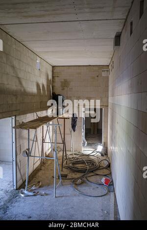 a mason works on a scaffold in a room without windows Stock Photo