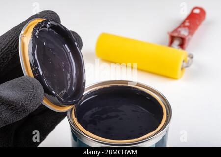 Black paint can and paint roller. Paint application accessories. Light background. Stock Photo