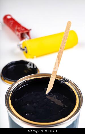 Black paint can and paint roller. Paint application accessories. Light background. Stock Photo