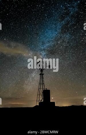 Windmill against vast starry sky, including the Milky Way and wispy clouds, above City of Rocks State Park, located between Silver City and Deming in Stock Photo