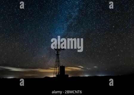 Windmill against vast starry sky, including the Milky Way, above City of Rocks State Park, located between Silver City and Deming in the Chihuahuan De Stock Photo