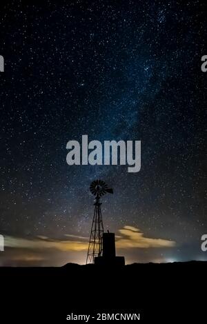 Windmill against vast starry sky, including the Milky Way, above City of Rocks State Park, located between Silver City and Deming in the Chihuahuan De Stock Photo