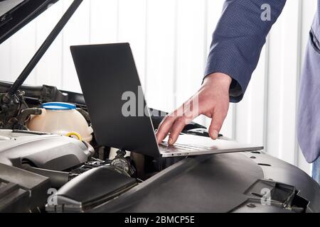Car mechanic using computer in auto repair shop Stock Photo