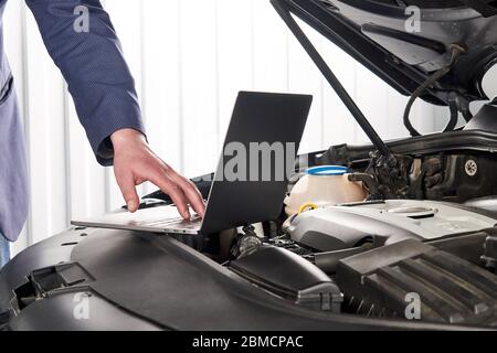 Car mechanic using computer in auto repair shop Stock Photo