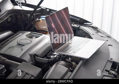 Laptop on a car in auto repair shop, Automobile mechanic repairman concept Stock Photo