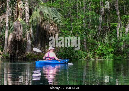 An active senior woman kayaks on the Silver River in Silver Springs State Park, Florida Stock Photo