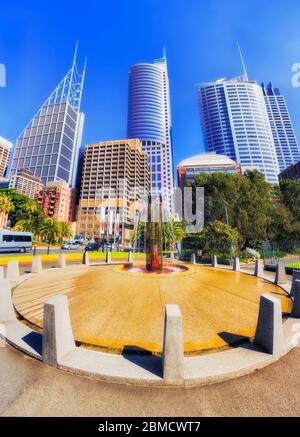 Bright sunny day in Sydney city CBD in front of talll office buildings under blue sky around small square with fountain. Stock Photo