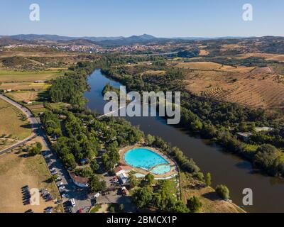 Happy people swimming on vacation. Aerial view over amazing pool. Drone point of view in summer landscape. Swimming pool in Mirandela, Portugal. Stock Photo