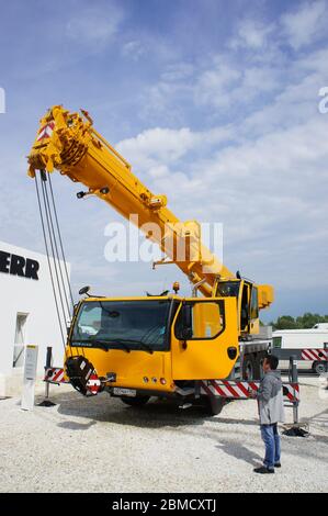 Moscow, Russia - June 4th, 2016: Vertical shot of crane operator using remote control to lower telescopic boom of mobile crane during trade fair CTT. Stock Photo