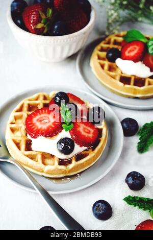 Homemade mini Waffles topped with fresh berries and cream, selective focus Stock Photo