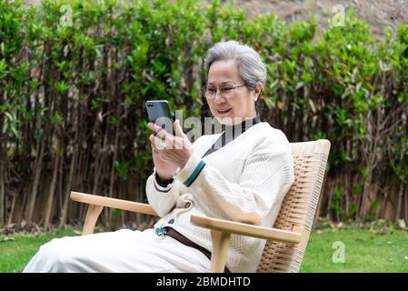 An Asian elderly woman is using a smartphone Stock Photo