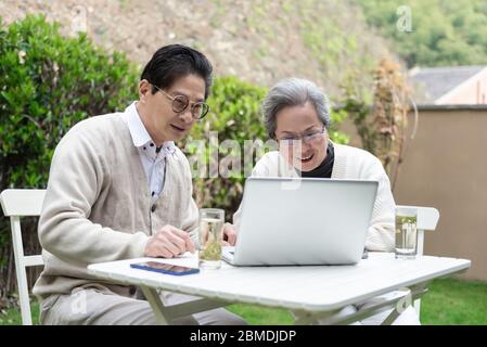 An Asian elderly couple is using a laptop Stock Photo