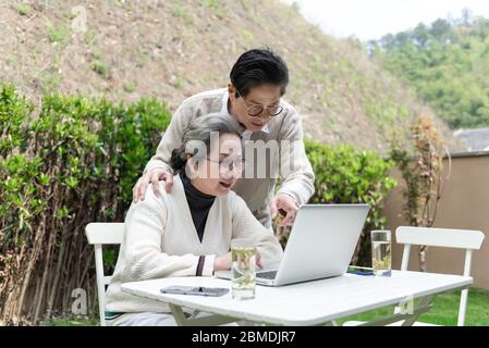 An Asian elderly couple is using a laptop Stock Photo