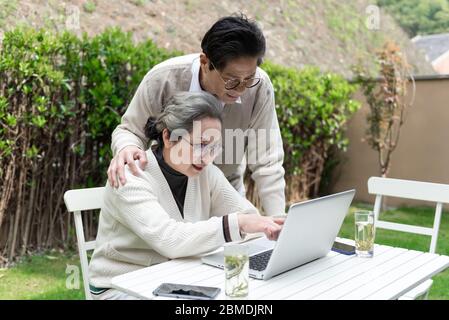 An Asian elderly couple is using a laptop Stock Photo