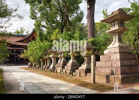 The view of the a traditional kaku-doro  (square) stone lanterns standidng along the pass at Kitano Tenmangu shrine. Kyoto. Japan Stock Photo