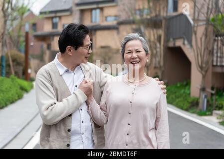 An Asian elderly couple walking in the community Stock Photo