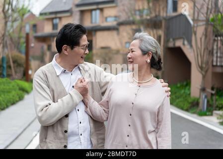 An Asian elderly couple walking in the community Stock Photo