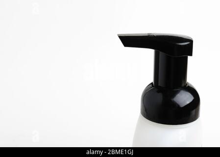 A close-up of the top portion of a black-and-white foaming hand soap dispenser set on a plain white background, Stock Photo
