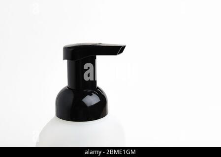 A close-up of the top portion of a black-and-white foaming hand soap dispenser set on a plain white background, Stock Photo