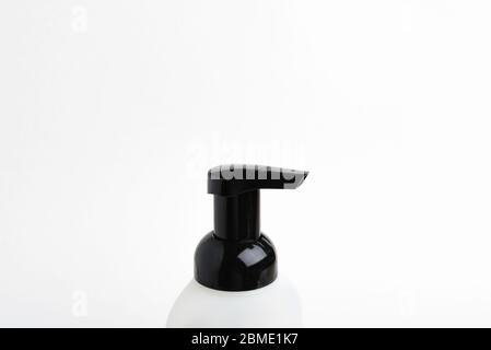 A close-up of the top portion of a black-and-white foaming hand soap dispenser set on a plain white background, Stock Photo