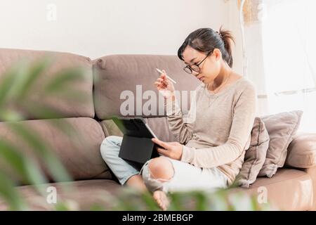 Young professional digital artist woman working from home. Asian freelance graphic designer girl thinking and looking for inspiration work from home Stock Photo